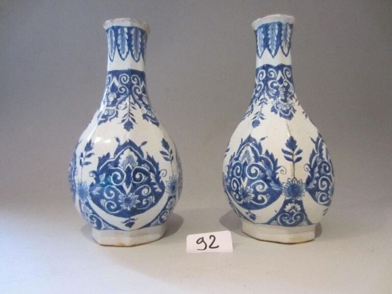 Paire de bouteilles à col à pans coupés décorées en camaïeu bleu de larges bandes de lambrequins fleuris et de godrons feuillagés sur les col