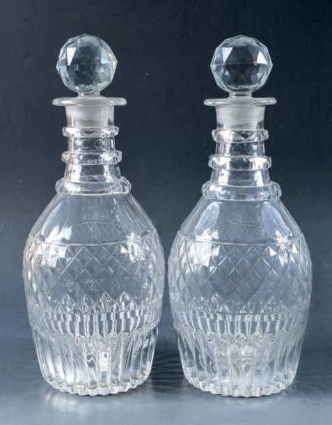 Paire de carafes à trois cordons de col et partie basse moulé à côte creuses, en cristal taillé à pointes de diamants et côtes plates; bouchons boules à facette