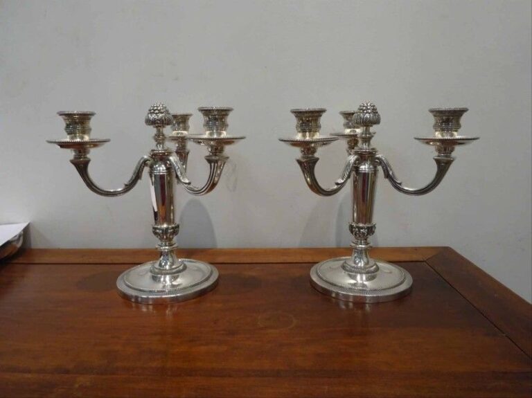 Paire de chandeliers à trois feux en métal argenté les prises en forme de pommes de pin