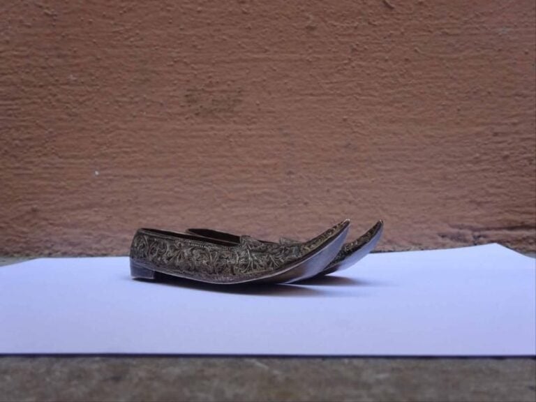 PAIRE DE CHAUSSURES DE MAHARADJA MINIATURES EN ARGENT REPOUSSE, JUTTIS Probable travail d'Inde du nord ouest et de Kutch, Epoque seconde moitié du XIXe siècle Ornées d'un charmant décor couvrant de volutes feuillagées et fleuries (manque un talon au dessous