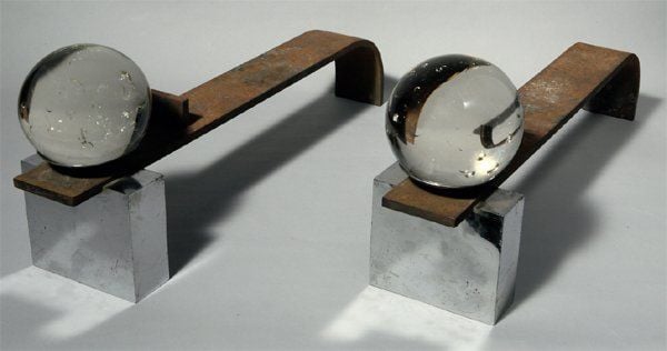 Paire de chenets à barres de support de buches à lames plates, courbes, en fer forgé et à tête en métal chromé et boule de verre transparen