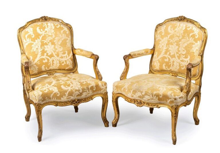 Paire de fauteuils en bois doré recouverts de tissu crème à décor de coquilles et rinceaux, bouquets fleuri