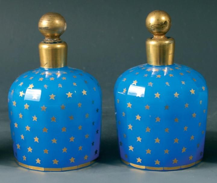 Paire de flacons à épaulement en opaline bleue taillée à côtes plates et ornée d'un semis d'étoiles dorées; bouchons boules en cristal dor