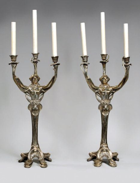 Paire de flambeaux « Cariatide » en bronze doré et patiné à trois bras de lumière en forme de fleurs sur socle polylobé à décor feuillag