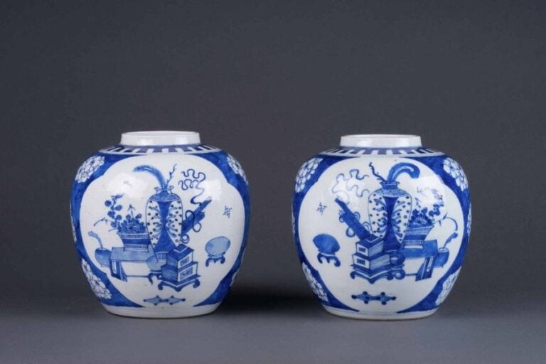 PAIRE DE JARRES A GINGEMBRE EN PORCELAINE BLEU BLANC A DECOR D'OBJETS AUSPICIEUX° Chine époque XXe siècle dans le style des productions de l'époque Kangxi De forme ovoïde à fond bleu cobalt tapissant qu'ornent des fleurs de prunus et sur lequel se détachent deux médaillons quadrilobés en réserve et inscrits de multiples objets auspicieux dont vases fleuris et rouleaux une frise de grecques sur le dessus de l'épaul