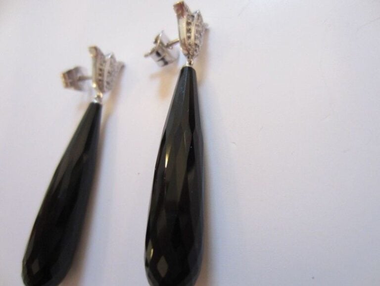 PAIRE DE PENDANTS D'OREILLES à motifs de «palmettes» en or gris serti de petits diamants retenant un long onyx piriforme facett