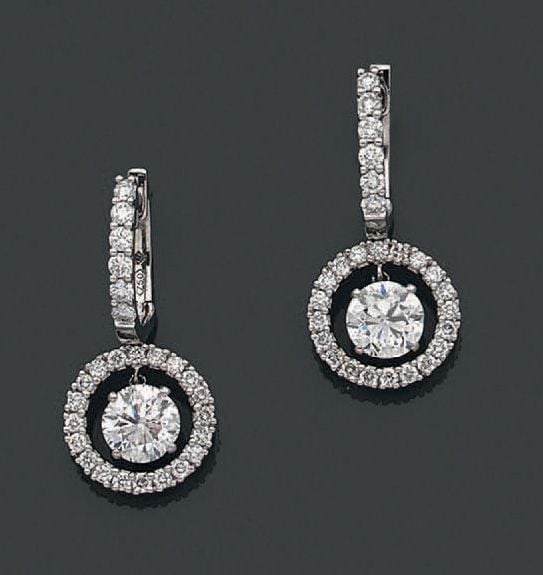 PAIRE de PENDANTS D'OREILLES circulaires en or gris (750 millièmes) ajouré serti de diamants taille brillant, dont un, en pampille, pesant 1,00 cara