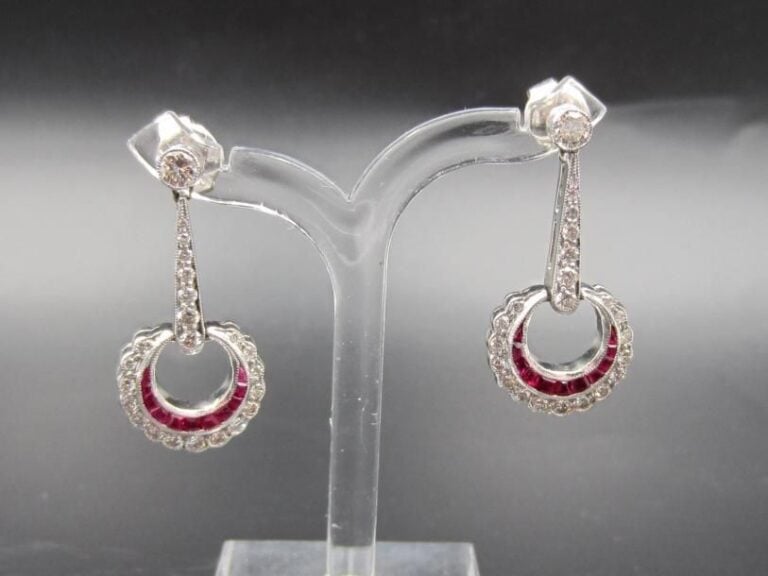 PAIRE de PENDANTS D'OREILLES en platine (950 millièmes) ajouré et articulé retenant un motif circulaire serti d'une ligne de rubis calibrés et diamant taille brillan