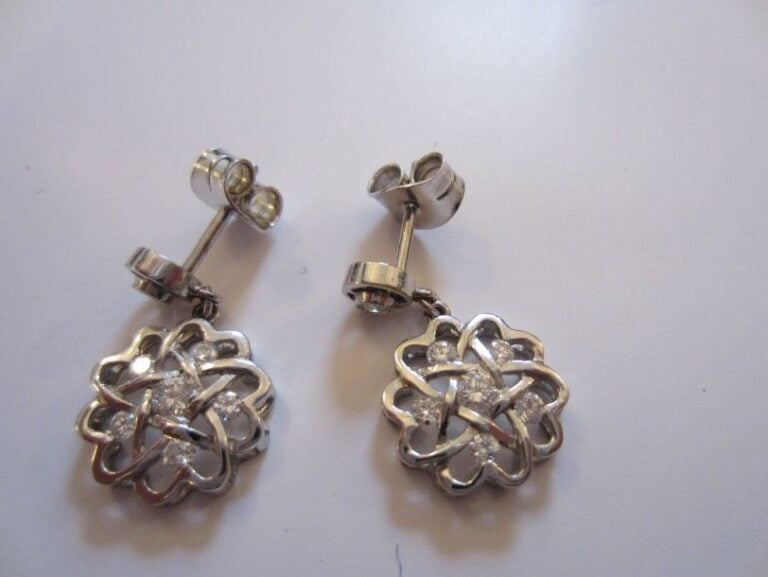 PAIRE DE PENDANTS D'OREILLES «fleur» en or gris ajouré serti de sept diamants taille brillant dont un plus important au centr