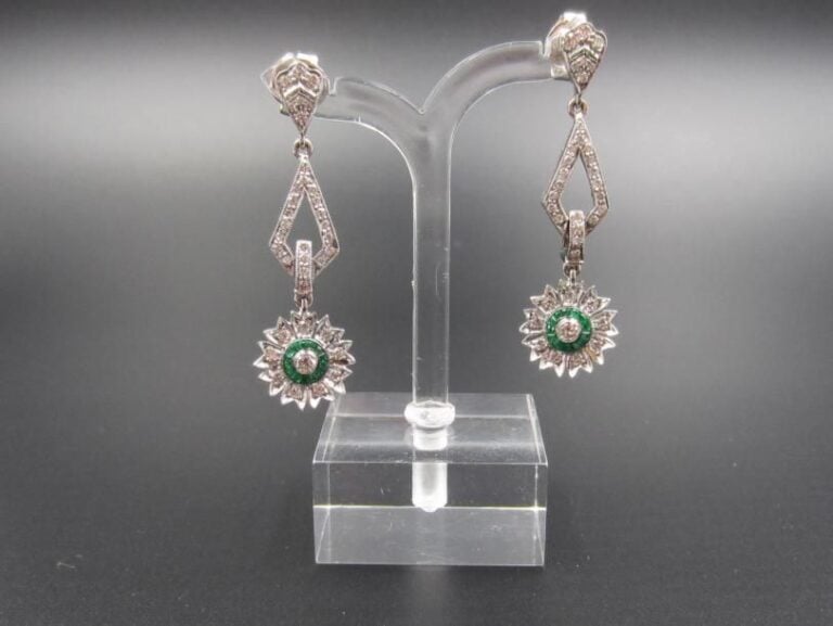 PAIRE de PENDANTS D'OREILLES «fleurettes» en or gris (750 millièmes) ajouré à motifs géométriques serti de diamants taille brillant et émeraudes calibrée