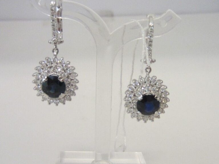 PAIRE DE PENDANTS D'OREILLES «marguerite» en or gris (750 millièmes) serti d'un saphir ovale dans un double entourage de diamants taille brillan