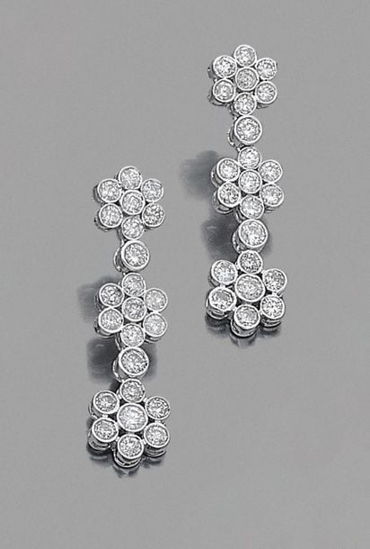 •Paire de PENDANTS d'OREILLES «trois fleurettes» en or gris (750‰) articulé, entièrement serti de diamants taille brillan