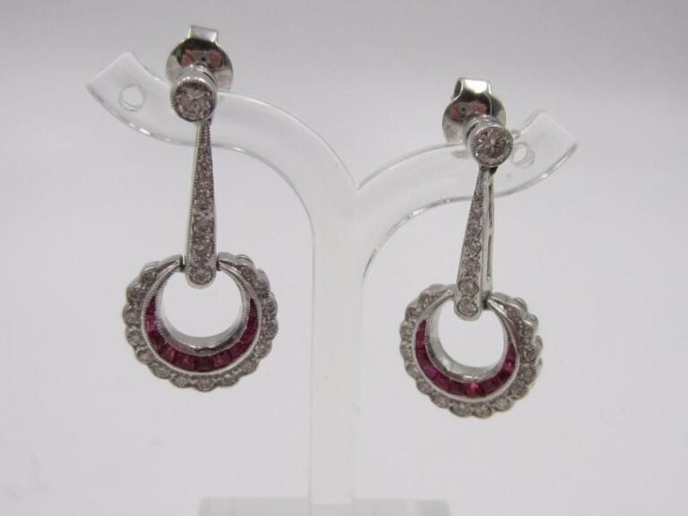 PAIRE de PENDANTS D’OREILLES en platine (800 millièmes) ajouré et articulé retenant un motif circulaire serti d’une ligne de rubis calibrés et diamant taille brillan