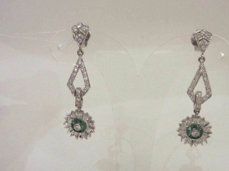 PAIRE de PENDANTS D’OREILLES « fleurettes » en or gris (750 millièmes) ajouré à motifs géométriques serti de diamants taille brillant et émeraudes calibrée