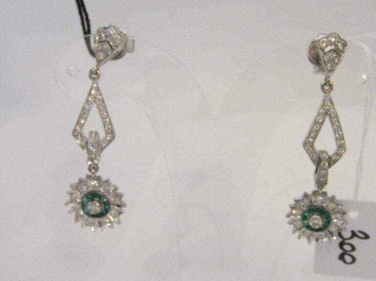 PAIRE de PENDANTS D’OREILLES « fleurettes » en or gris (750 millièmes) ajouré à motifs géométriques serti de diamants taille brillant dont un, plus important, et émeraudes calibrée