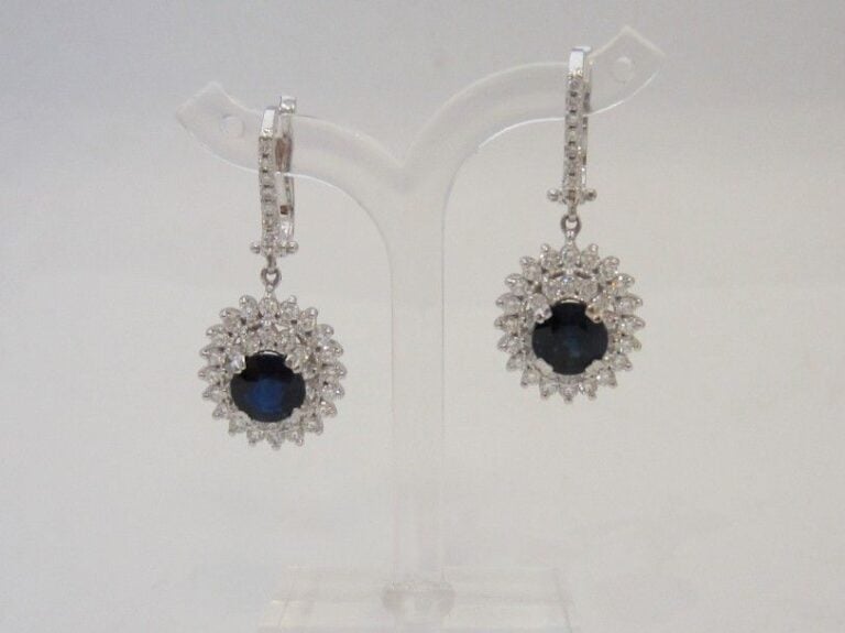 PAIRE de PENDANTS D’OREILLES « marguerites » en or gris (750 millièmes) serti d’un saphir ovale dans un double entourage de diamants taille brillan