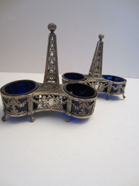 Paire de salières doubles en argent à décor ajouré figurant des chérubins jouant de la trompe, des guirlandes fleuries et des entrelacs feuillagés; la prise centrale en colonn