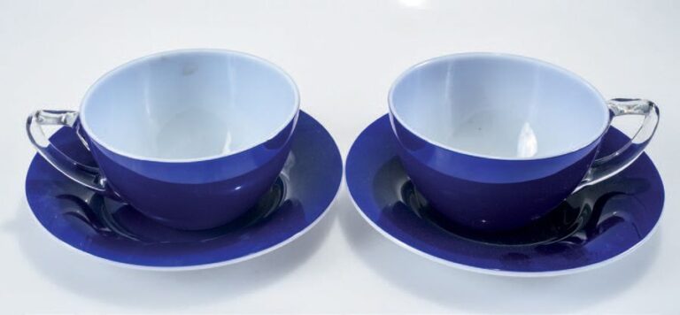 Paire de tasses et sous-tasses doublées d'émail bleu sur opaline blanche; anses incolor