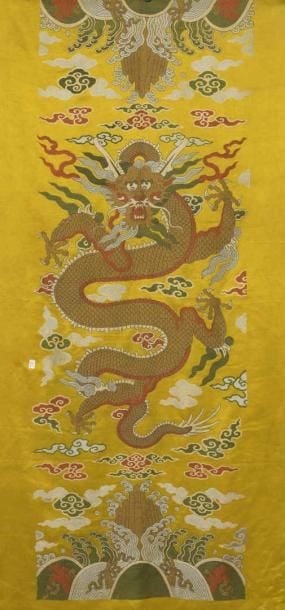 PANNEAU DE SATIN DE SOIE BRODE D'UN DRAGON ARCHAIQUE Chine, Fin de la Dynastie Qing, Vers 1900 De forme rectangulaire, vertical et pour suspension murale, il est fait d'un panneau de satin de soie jaune brodé d'un dragon à cinq griffes archaïque et frontal volant sur un fond de volutes nuageuses et qu'encadrent deux rangs de vagues lishui, chaque centré des monts sacrés (quelques usures et fils tirés