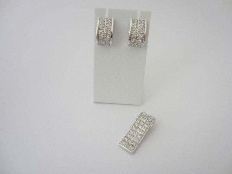PARURE comprenant une PAIRE DE BOUCLES D?OREILLES et un PENDENTIF en or gris (750 millièmes) serti de lignes de diamants taille brillan