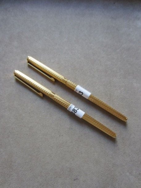 PARURE de deux STYLOS comprenant un stylo à plume et un roller en or jaune guilloché à motif ondul