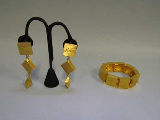 PARURE en métal doré strié à décor de petits carrés articulés comprenant un BRACELET et une PAIRE de PENDANTS d'OREILLES (signée)