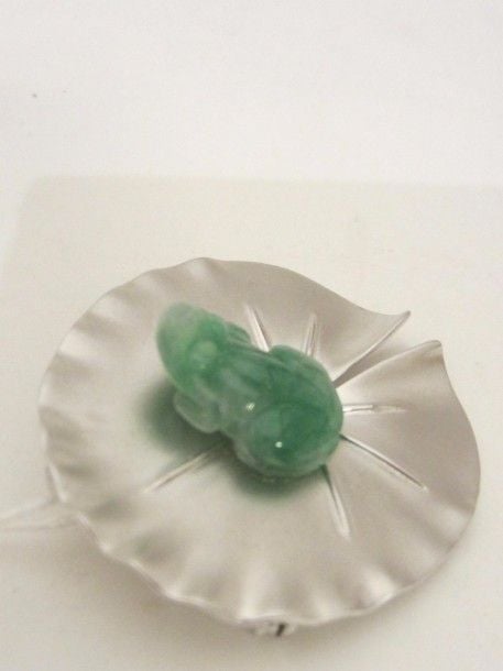 PENDENTIF BROCHE « nénufar » en or gris (750 millièmes) satiné, ciselé et juponné surmonté d’une grenouille en jade jadéïte sculpt