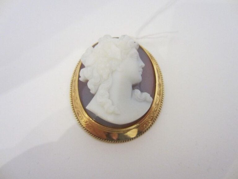PENDENTIF BROCHE ovale en or jaune (750 millièmes) ciselé serti d’un camée profil de femme de cornaline, léger fêle