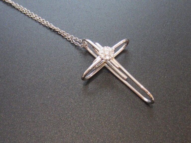 PENDENTIF «croix» «trombones entrelacés», et sa chaînette, en or gris (750 millièmes) centré d'une fleur serti de diamants taille brillan