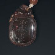 Pendentif en ambre avec inscriptions en chinois et en mandchous, surmonté d'un féli