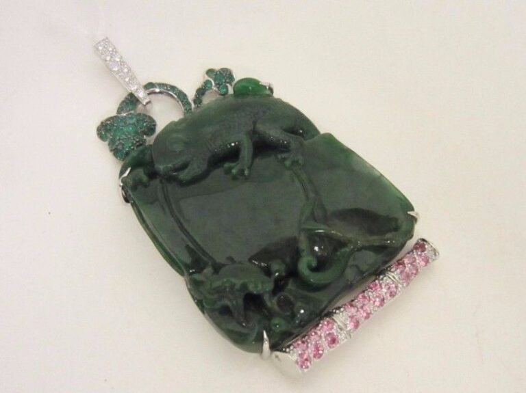 PENDENTIF en or gris (750 millièmes) ajouré orné d’un jade néphrite sculptée à motif d’ « iguane dans la nature » épaulé de pavages de grenats verts, saphirs roses et diamants taille brillan