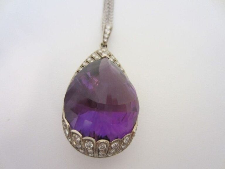 PENDENTIF, et sa triple chaînette, en or gris (750 millièmes) serti d?une importante améthyste entièrement facettée et taillée en poire soulignée de diamants taille brillan