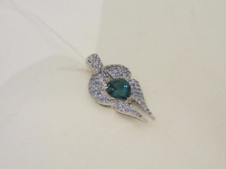 PENDENTIF « géométrique » en or gris (750 millièmes) serti d’une tourmaline bleue-verte piriforme, entourée de pavages de topaze