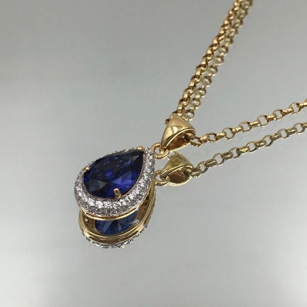 PENDENTIF «goutte» et une CHAINETTE en or jaune (750 millièmes), serti d'une pierre bleue piriforme et pavages de pierres blanche