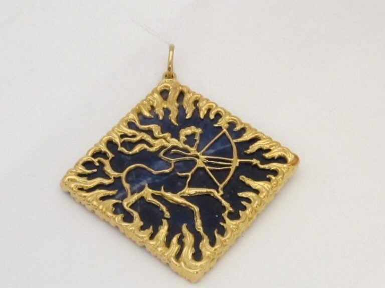 PENDENTIF losangique « sagittaire » en or jaune (750 millièmes) ajouré et ciselé retenant une plaque carrée d’agate bleue (fèles