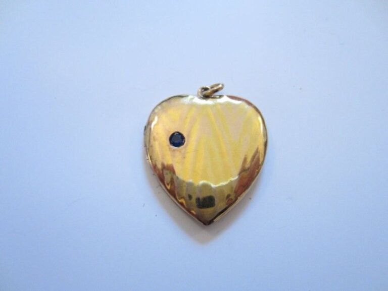 PENDENTIF PORTE-SOUVENIR "coeur" ouvrant à charnière en or jaune anciennement godronné serti d'un saphir ron