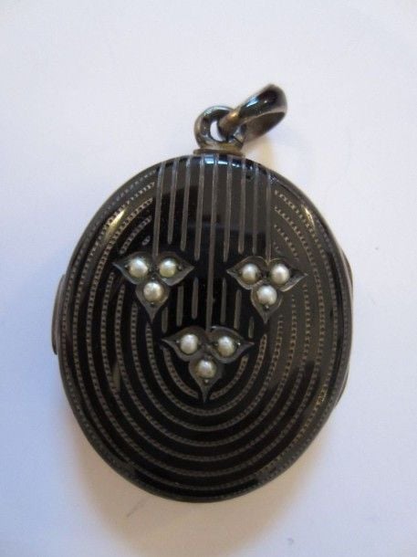 PENDENTIF «porte souvenir» ovale en argent émaillé de noir, guilloché, pointillé et serti de neuf demi-perle