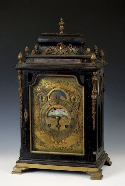 Pendule en bois noirci mouluré agrémentée de bronze ciselé et doré tels que graines, vases couverts, chutes à termes et motifs rocaill