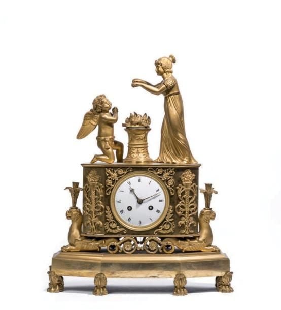 Pendule en bronze doré et ciselé à décor au sommet d'une allégorie de l'amour reposant sur une borne flanquée de griffon