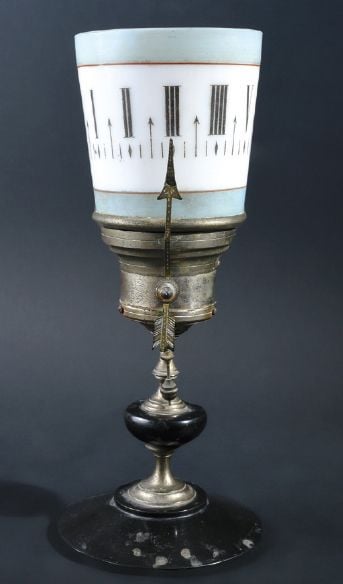 Pendule veilleuse sur pied composée d'un godet tournant en opaline blanche peinte des chiffres marquant les heures; pied en métal et ony