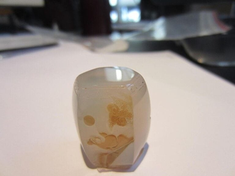 Petit pendentif hexagonal en forme de tabouret, en agate translucide à décor en léger relief dans une veine beige représentant un philosophe auprès d'un lingzhi, sous la lun