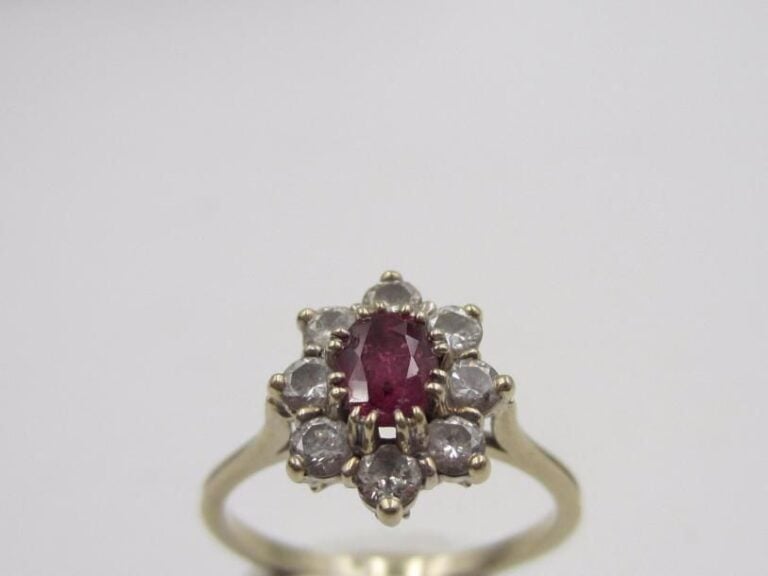 Petite BAGUE « marguerite » en or gris (750 millièmes) serti d’un rubis de forme ovale entouré de diamants taille brillan