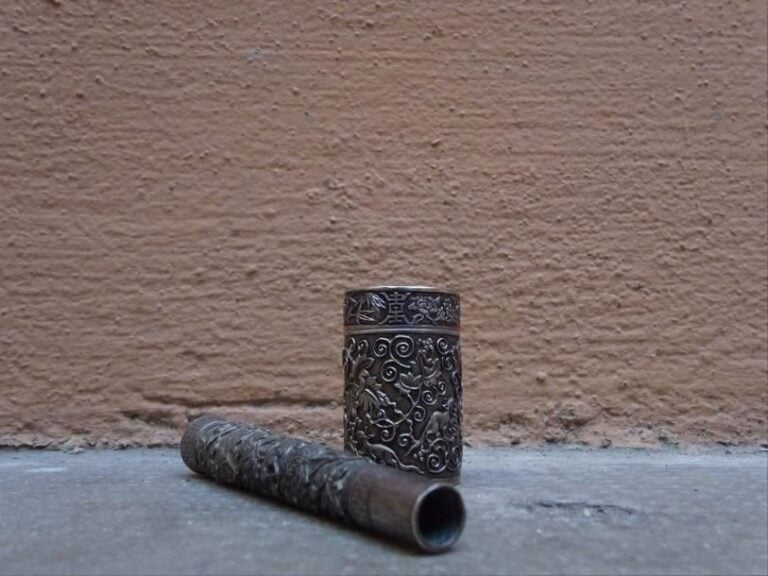 PETITE BOITE A OPIUM COUVERTE DE FORME CIRCULAIRE EN ARGENT Indochine, Travail des alentours de 1900 Elle est ornée d'un décor en léger relief sur fond guilloché aux raisins parmi rinceaux et raisins, de caractères Shou (longévité) sur le dessus et le pourtour du couvercl