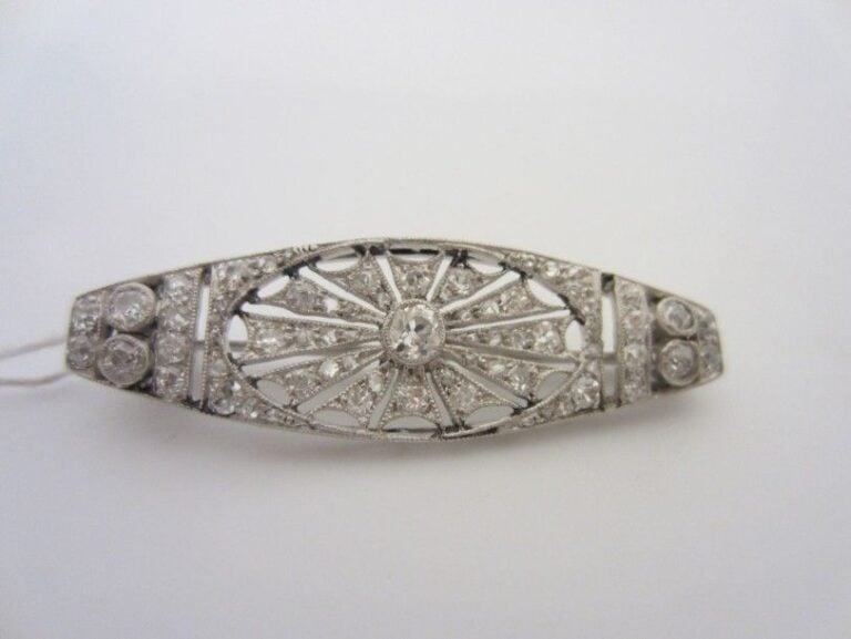 Petite BROCHE en platine (900 millièmes) et or gris (750 millièmes) ajourés, sertis de diamants à motif rayonnan