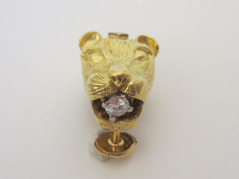 PIN'S «tête de lionne» en or jaune (750 millièmes) ciselé serti de quatre diamants taille brillan