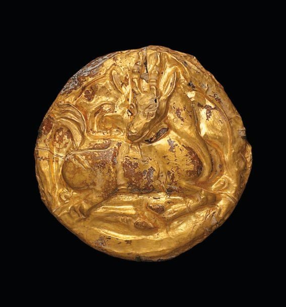PLAQUE À L'ANTILOPE Plaque discoïde en fer recouverte d'une feuille d'or repoussée, décorée d'une antilope couchée, tête de trois-quarts tournée en arrièr