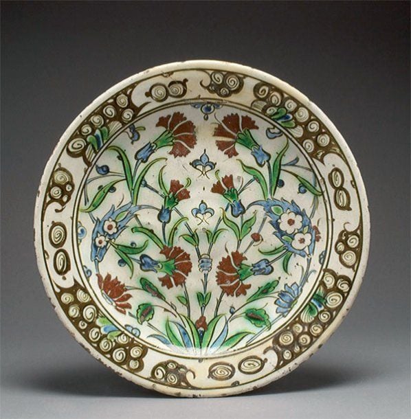 PLAT AU DÉCOR FLORAL Plat décoré en polychromie et engobe rouge sur engobe blanc d'oeillets et d'églantines et de « vagues et rochers » sur le marl