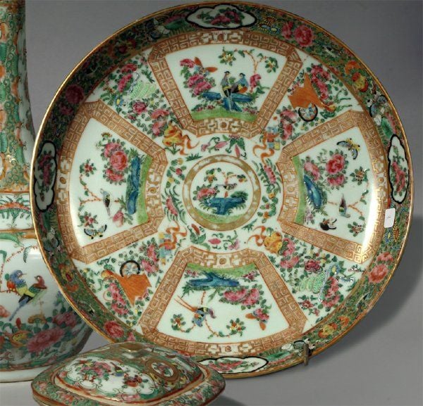 Plat en porcelaine de Canton à décor de réserves avec oiseaux, papillons, rochers et fleurs alternant avec des paniers fleur