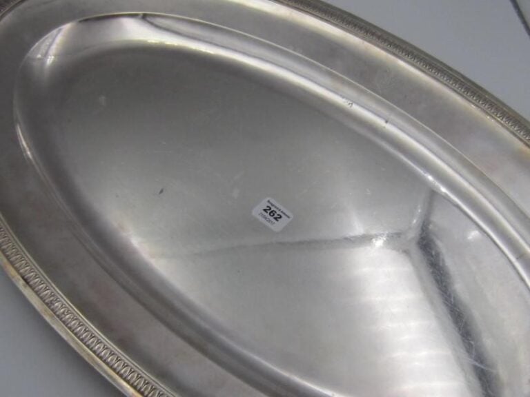Plat ovale en argent à bordure de feuilles d'eau; écusson chiffré