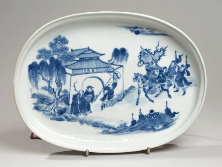Plat ovale en porcelaine à décor en bleu sous couverte d'un général arrivant à cheval près d'une porte encadrée de saule